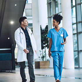 two healthcare professionals talking and walking together in a modern hosiptal