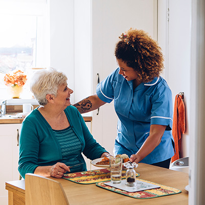 a carer helping an elderly lady by providing here with her dinner