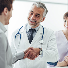 a male doctor shaking hands with another health professional