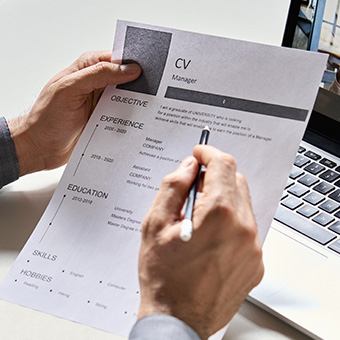 a man holding a printed CV in front of a laptop