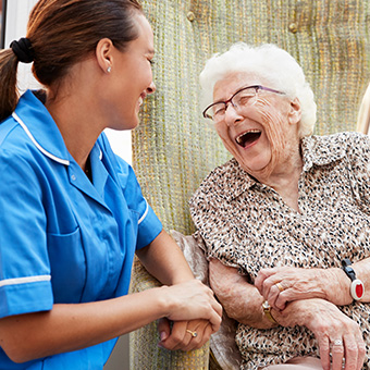 an elderly lady laughing with a carer