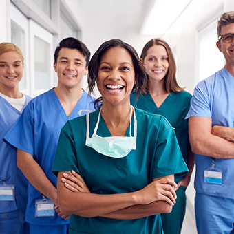 a group of nurses standing together and smiling at the camera in a hallway