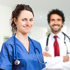a nurse smiling at the camera with a doctor in the background